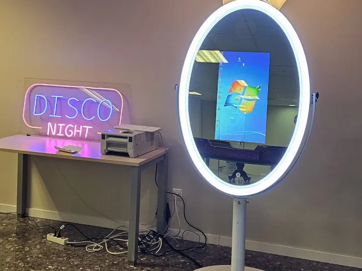 Espejo mágico con pantalla de inicio junto a un letrero de neón