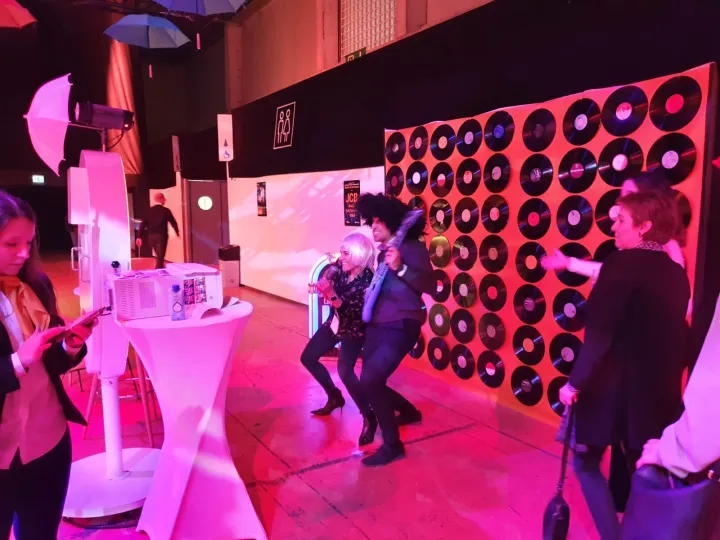 Invitados posando ante el espejo mágico junto a un photocall de vinilos