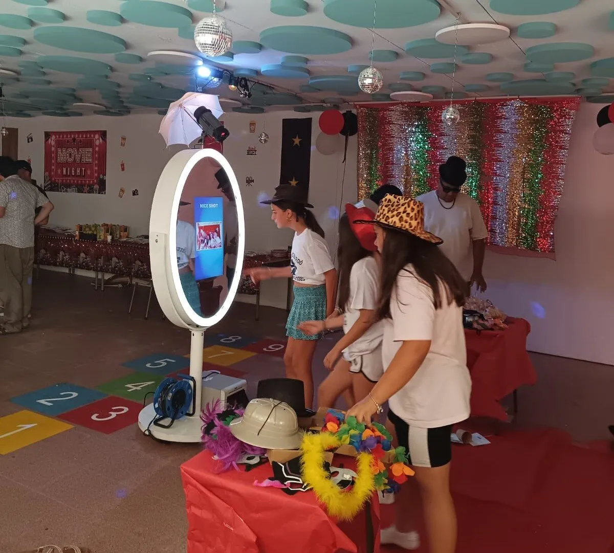 Grupo de invitados con gafas y sombreros de atrezo ante el espejo mágico