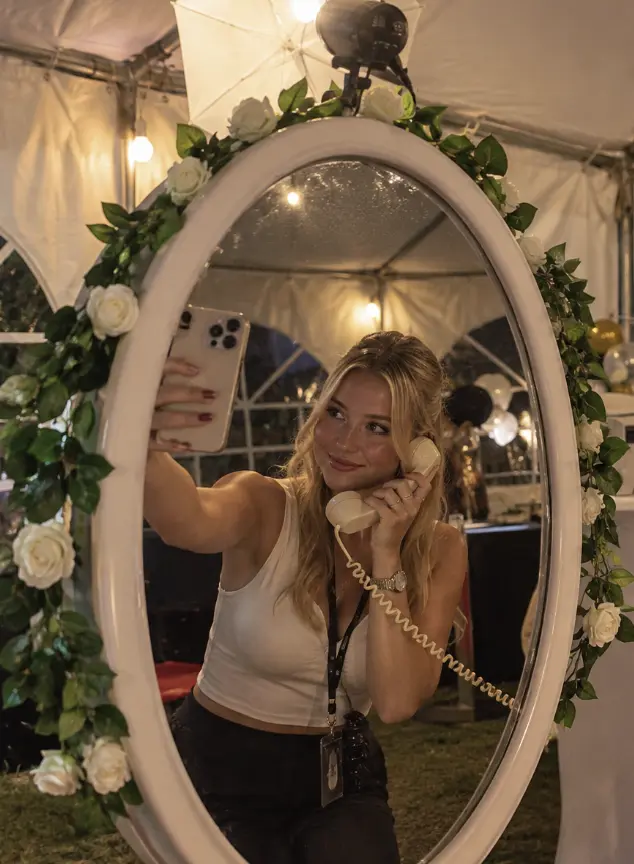 Chica haciéndose un selfi con un teléfono de época en el fotomatón espejo mágico